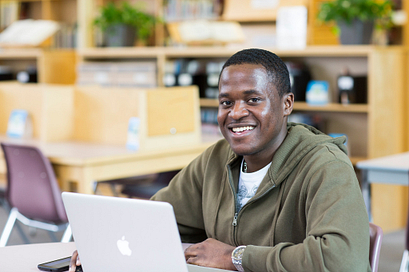 Male student smiling while working on his laptop